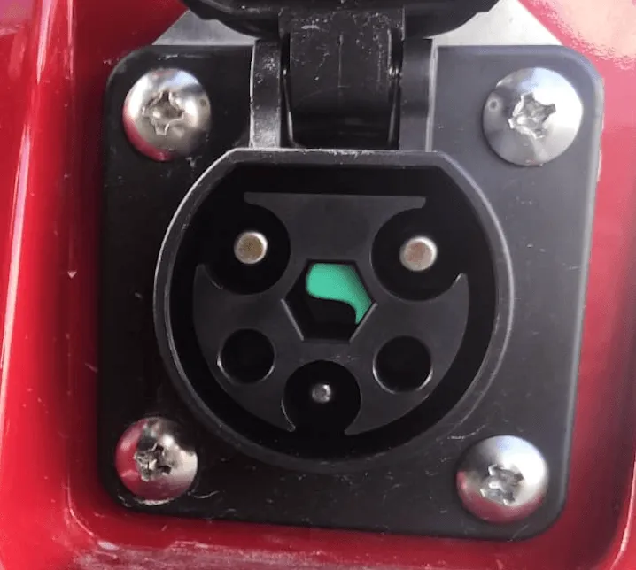 Toma de carga con la tapa abierta en un carrito de golf rojo