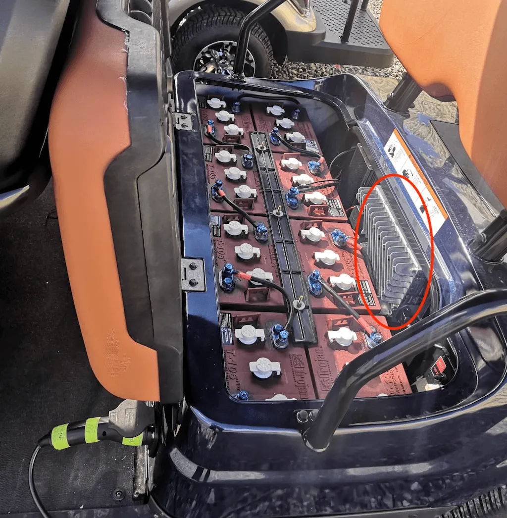 Compartimiento de las baterías bajo el asiento, con el cargador integrado marcado